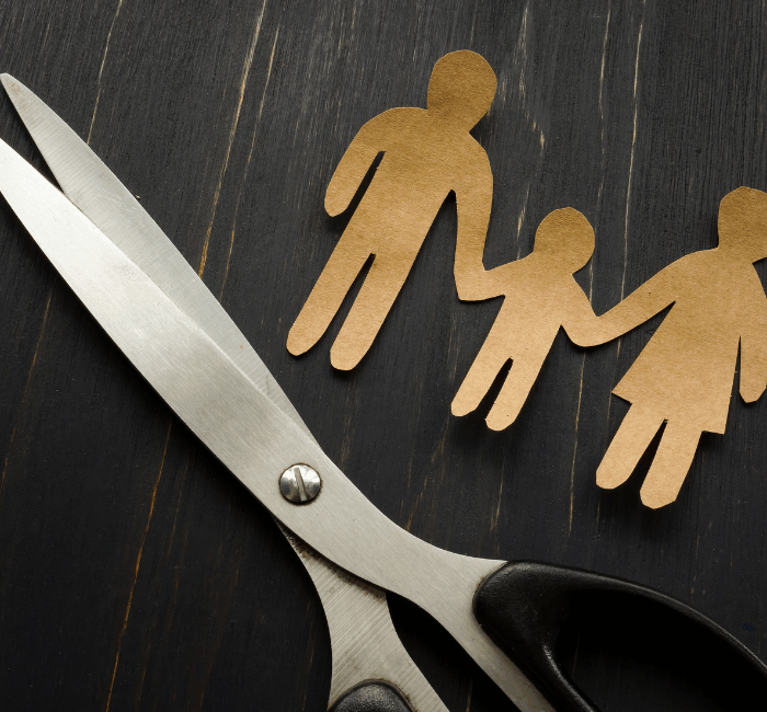 Paper cut out family with a pair of scissors to represent parental alienation